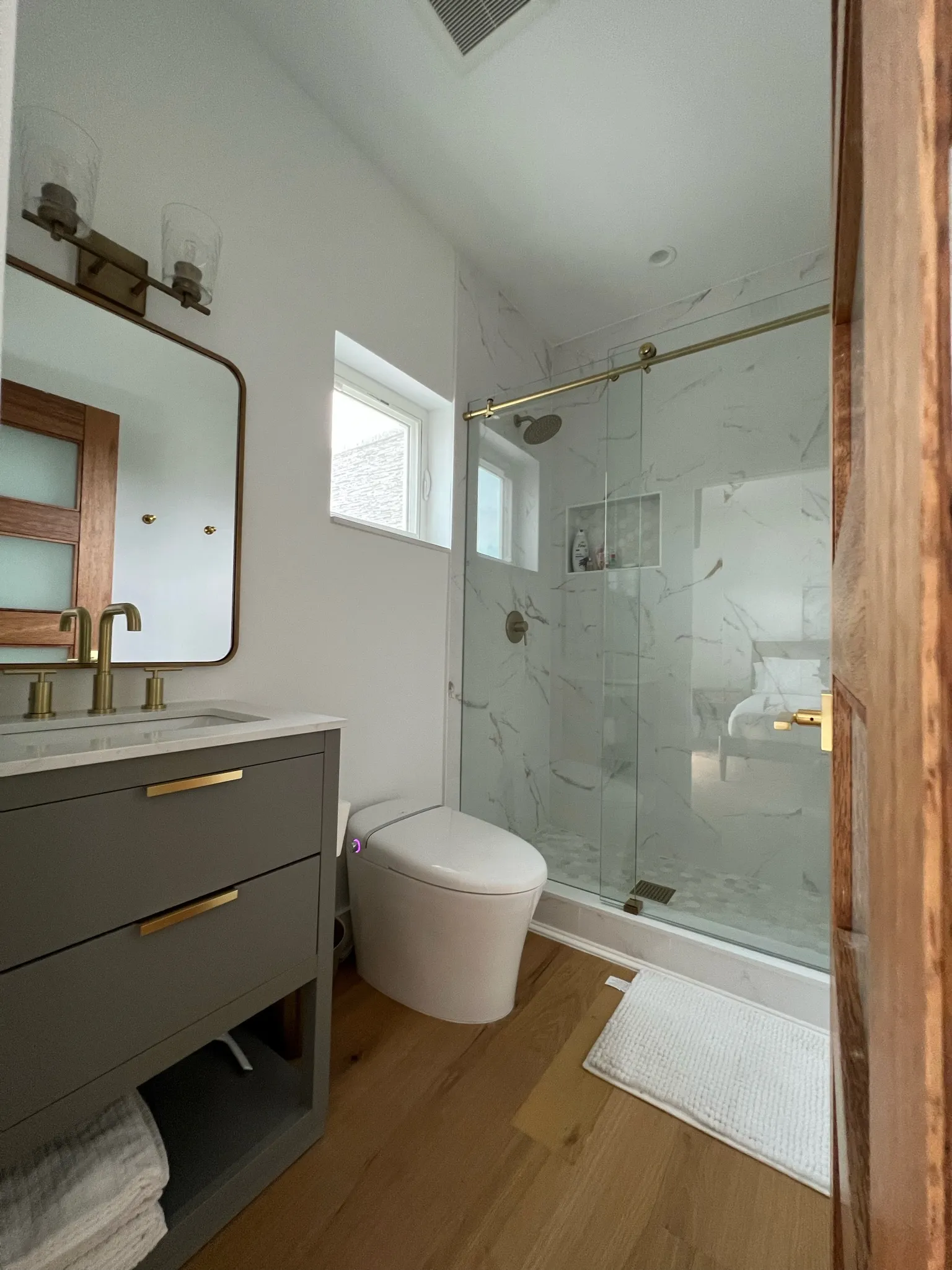 Secondary bath — gray vanity, marble shower, gold trim